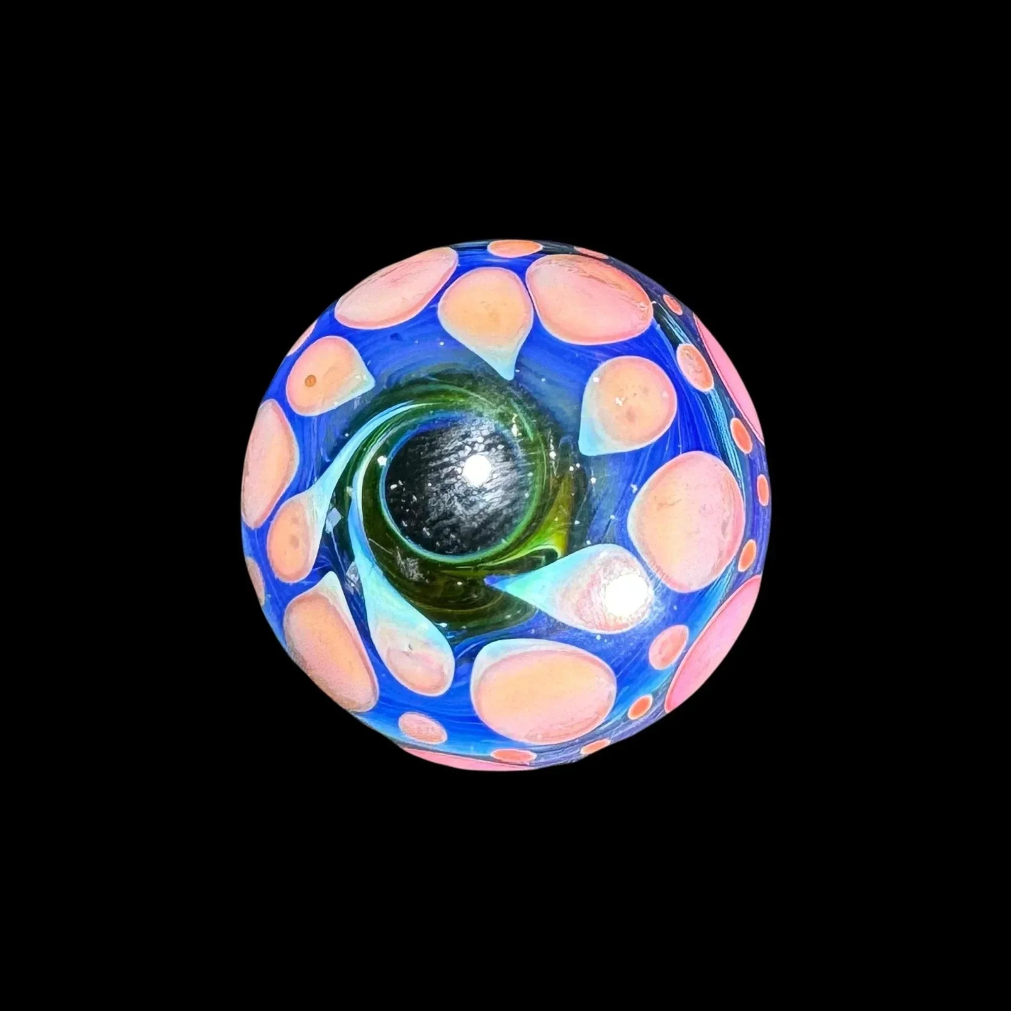 Hand-blown glass marble with blue swirls and pink dots on a black background