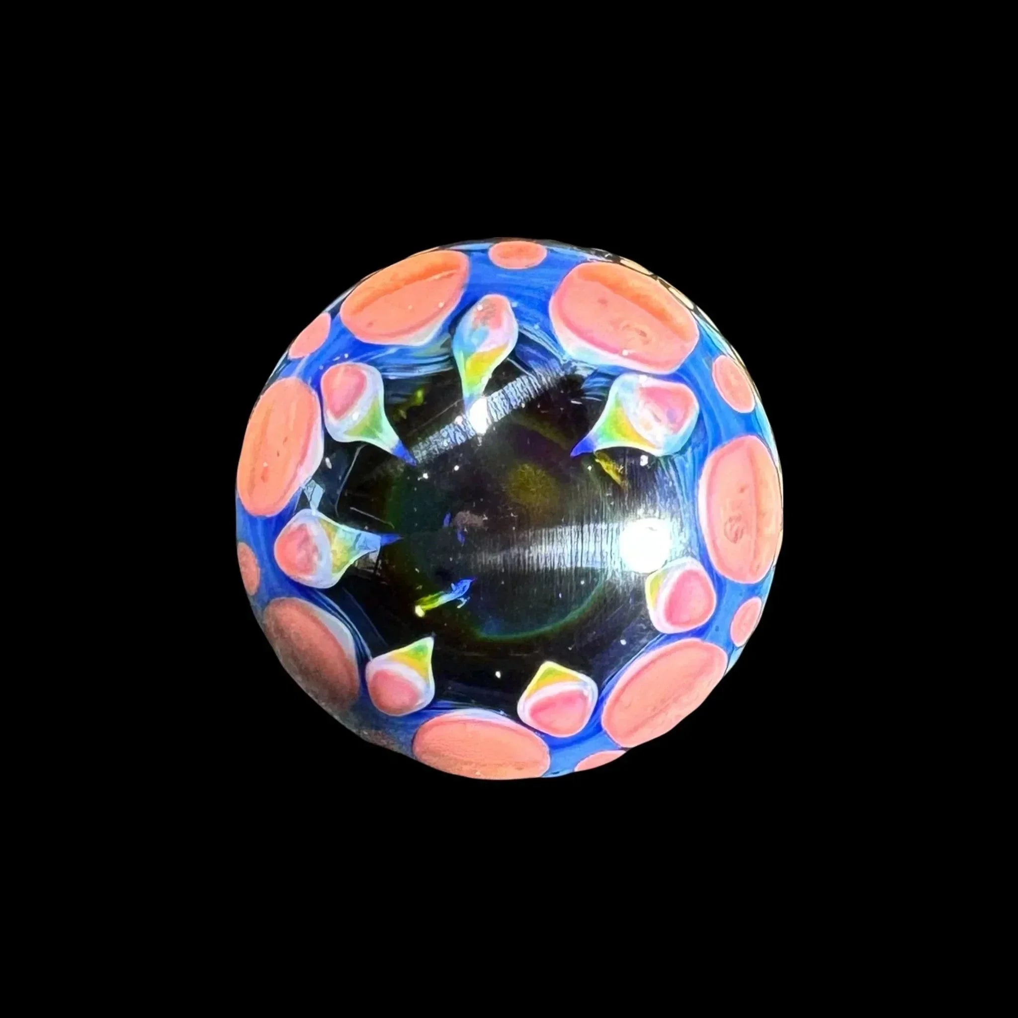 Colorful glass marble with blue and pink dot design, heady glass accessory on black background