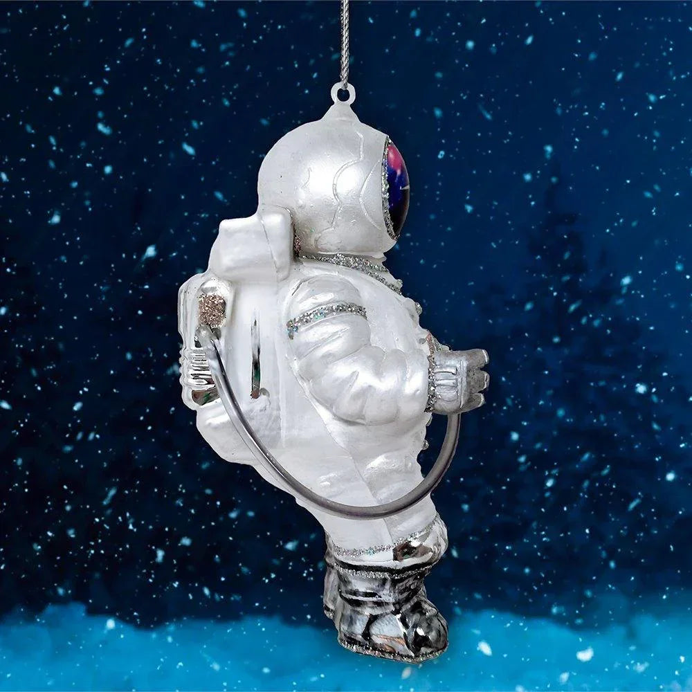Silver astronaut ornament hanging against a snowy night sky background