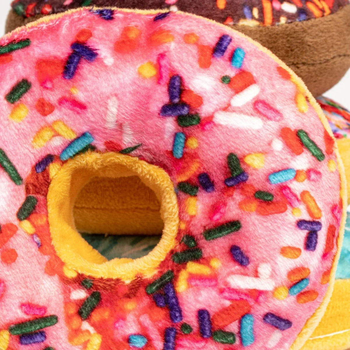 Plush pink donut pillow with colorful sprinkles and a yellow center, soft toy decor.