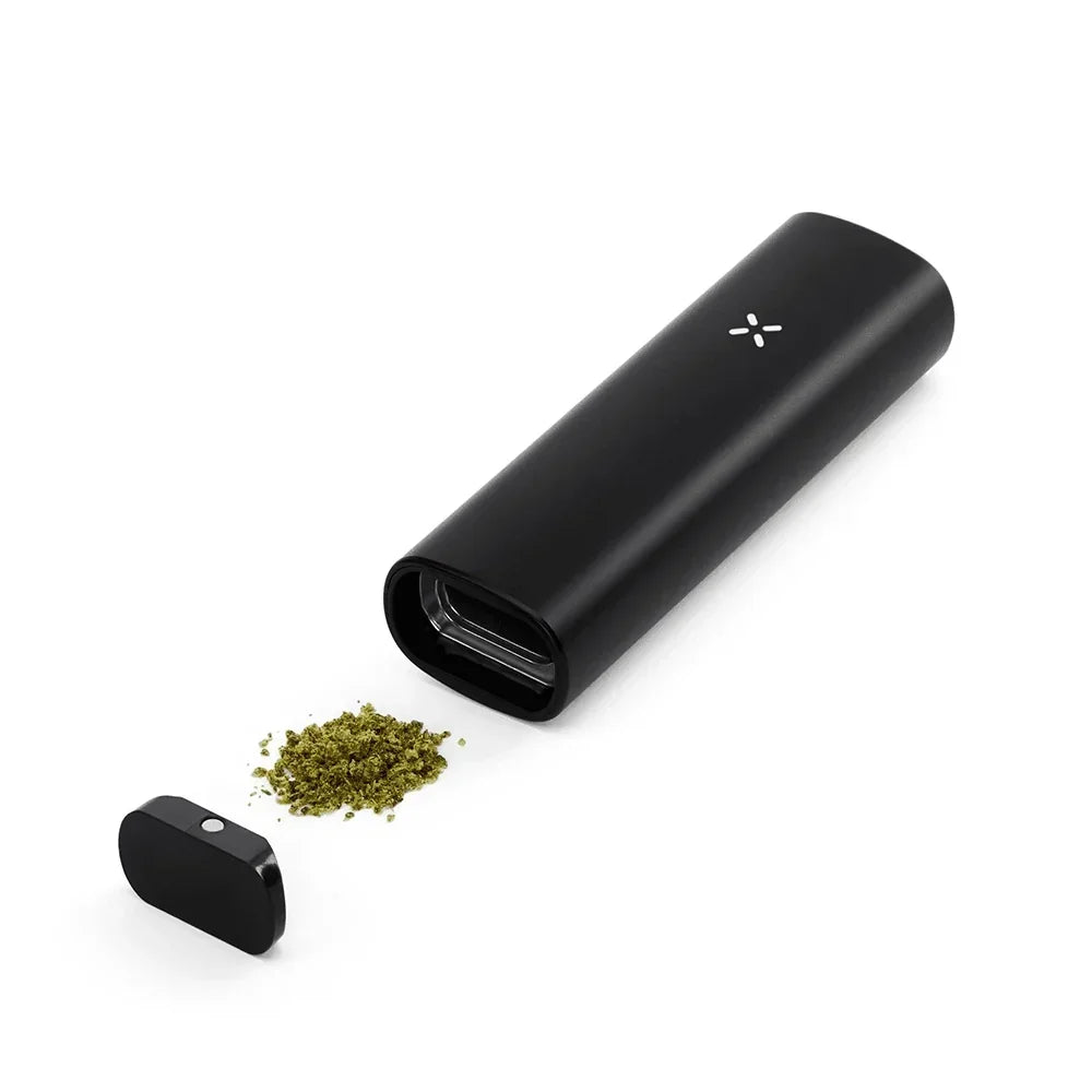 Black dry herb vaporizer with open chamber and loose herbs on white background