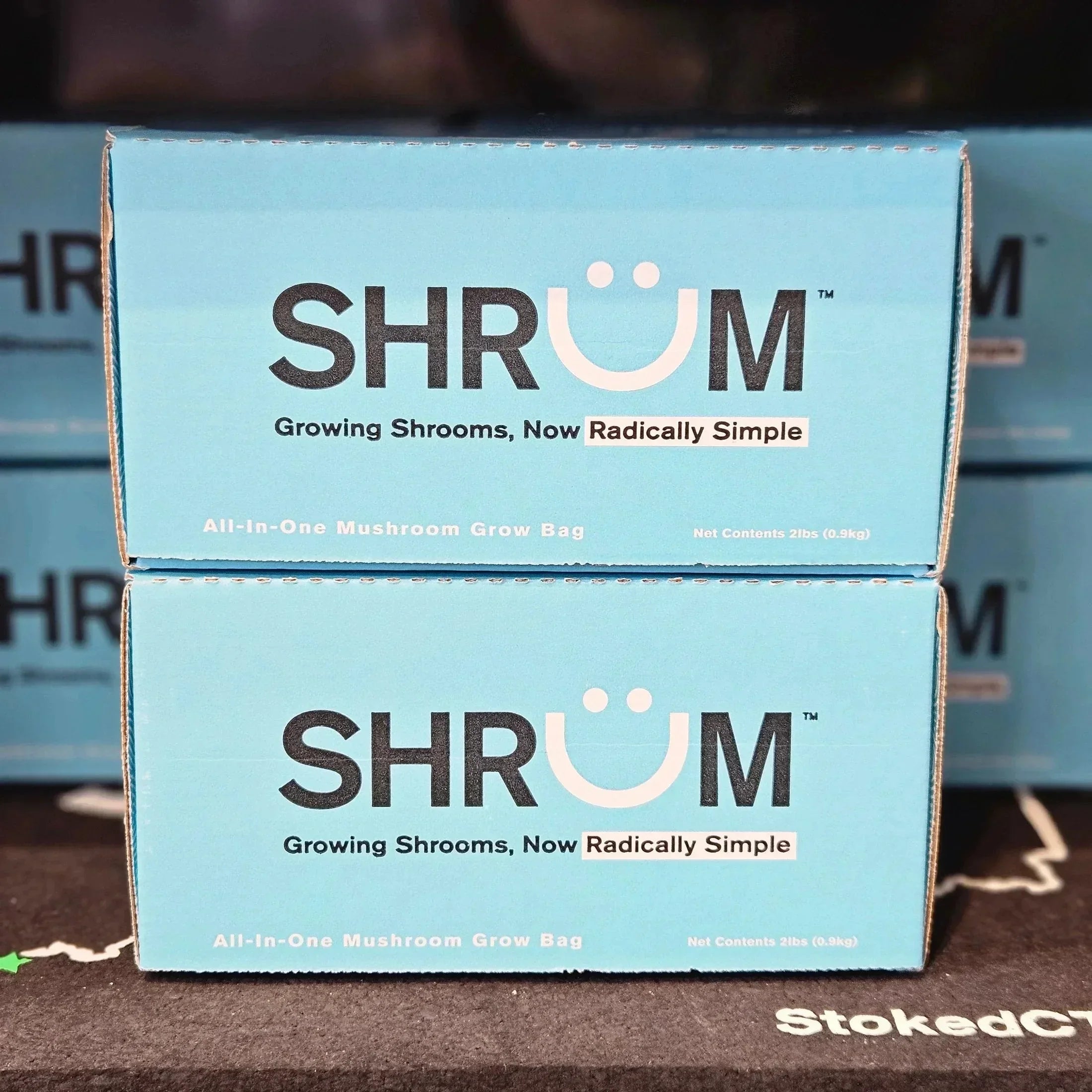 Two blue SHRÜM all-in-one mushroom grow bag boxes stacked on a counter