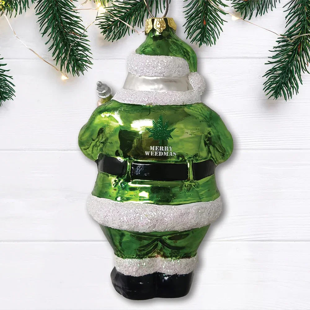Green Santa ornament with 'Merry Weedmas' and cannabis leaf, hanging on Christmas tree