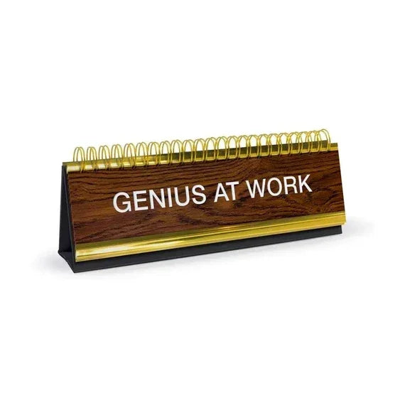 Desk sign with wood finish and gold accents reading GENIUS AT WORK, office accessory