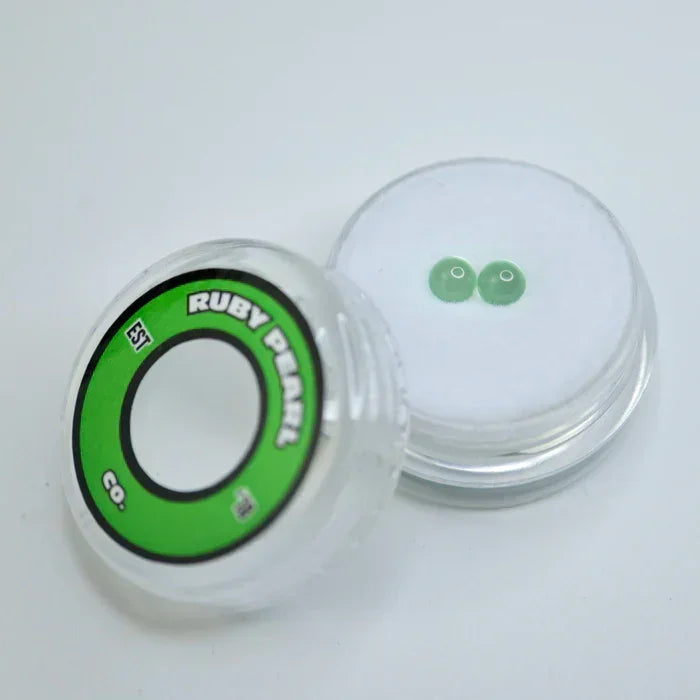 Two green terp pearls in a clear storage container on a white background
