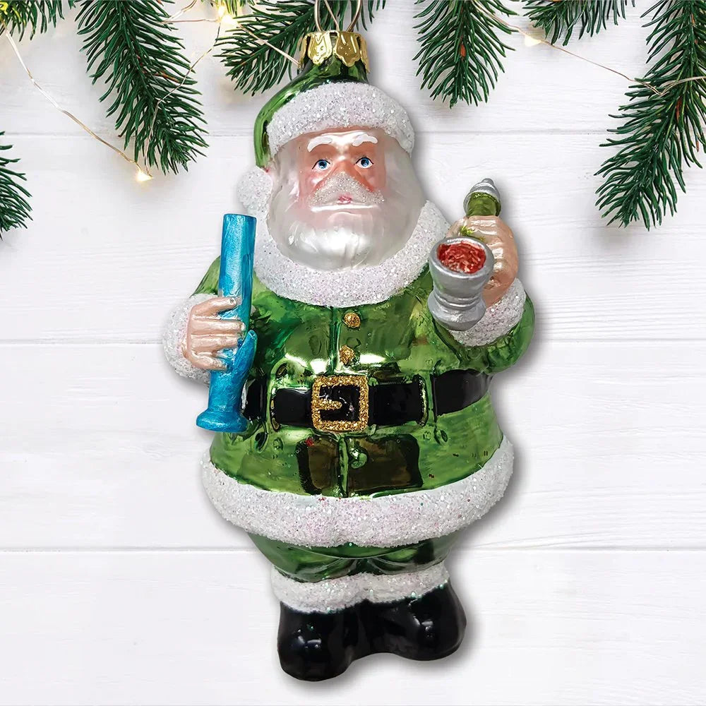 Green Santa ornament holding glass pipe and goblet, Christmas tree branches above.