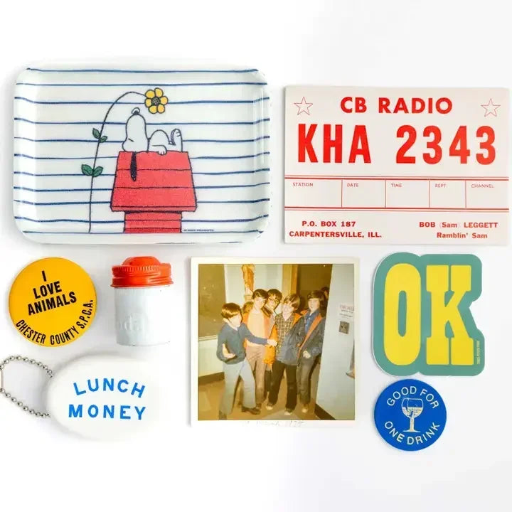 Vintage Snoopy doghouse tray with retro buttons, stickers, and a Polaroid photo flat lay.