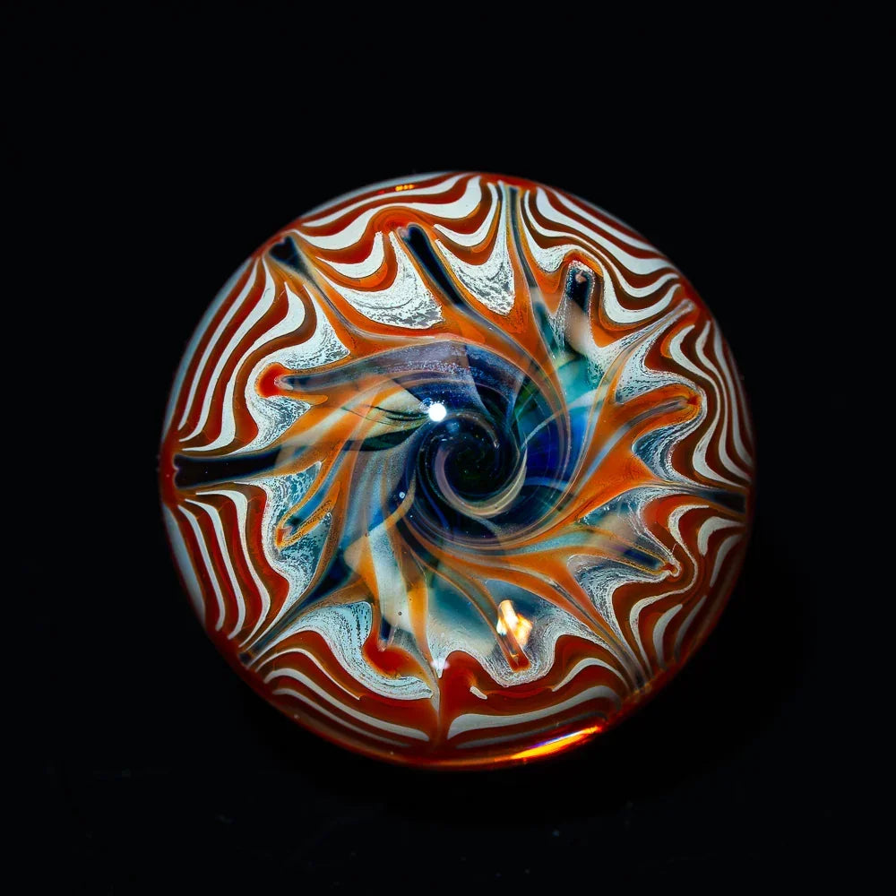 hand blown glass marble with intricate red, white, and blue swirl design on black background