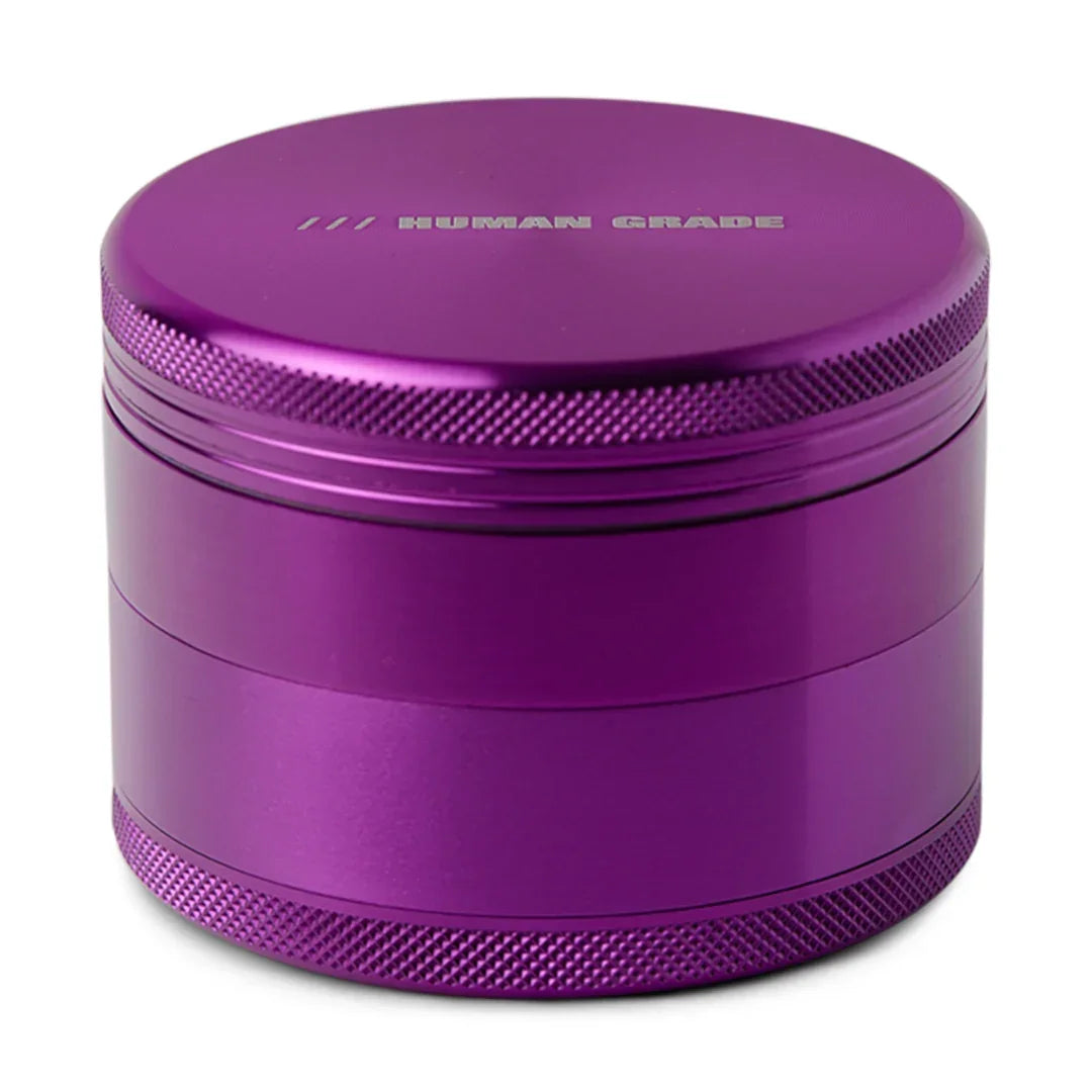 Purple aluminum herb grinder with textured grip and 'HUMAN GRADE' text on top.