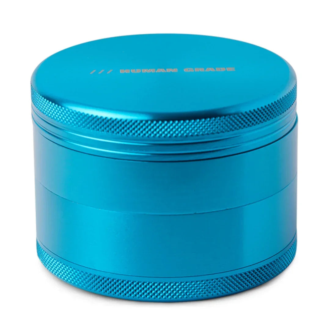 Blue metal herb grinder with textured grip and 'HUMAN GRADE' text on the lid