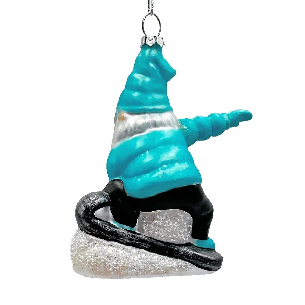 Glass ornament of a blue and white snowboarding gnome on sparkling snow with a hanging loop
