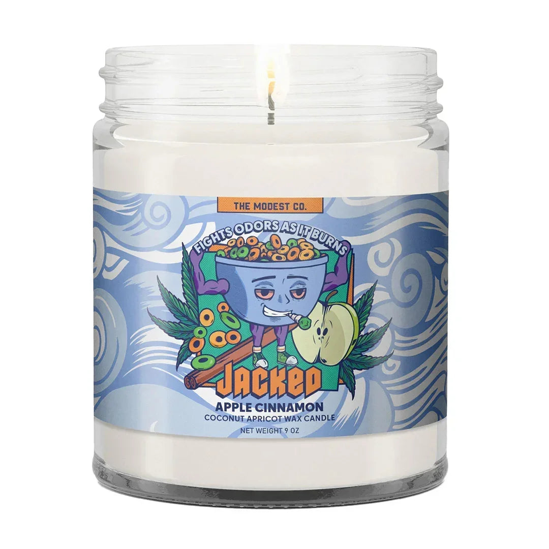 Apple cinnamon scented candle in glass jar with colorful label, burning wick visible