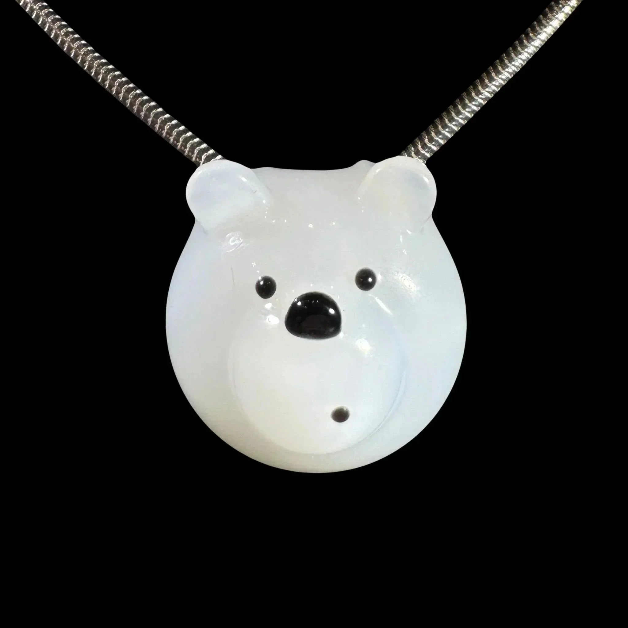 White glass bear pendant necklace with metal chain on black background