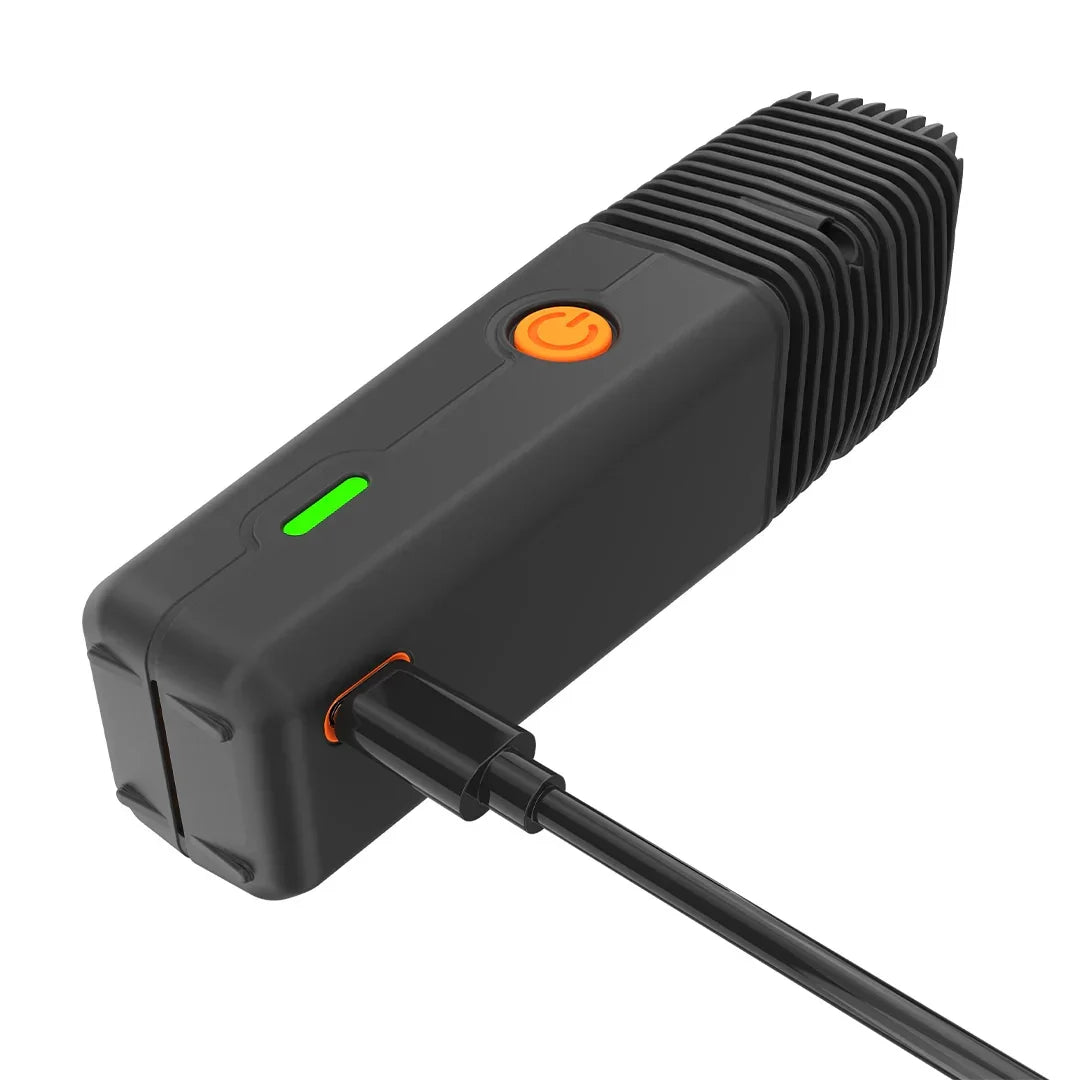 Portable dry herb vaporizer charging, black with green LED light and orange power button.