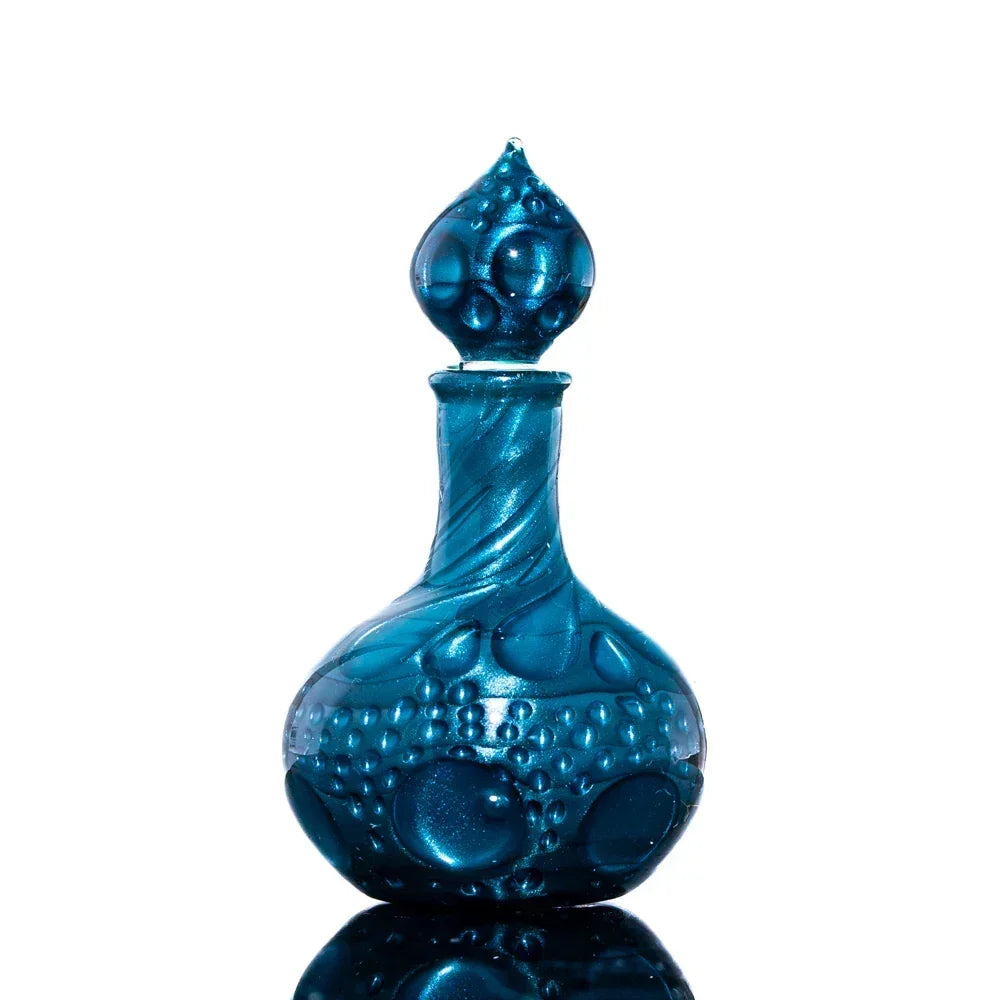 Blue textured glass bottle with bubble patterns and decorative stopper on white background