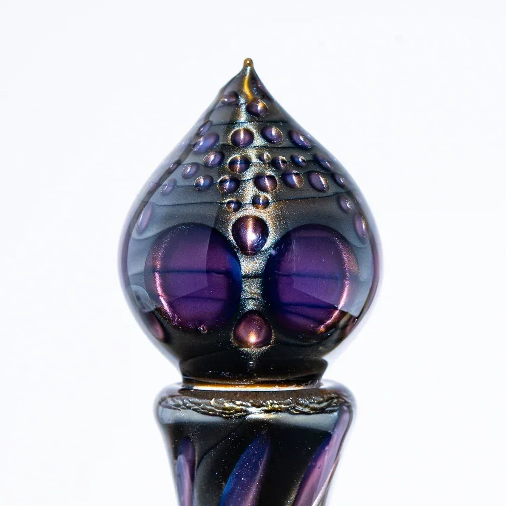 Handcrafted glass art piece with purple and metallic accents, teardrop shape, close-up view