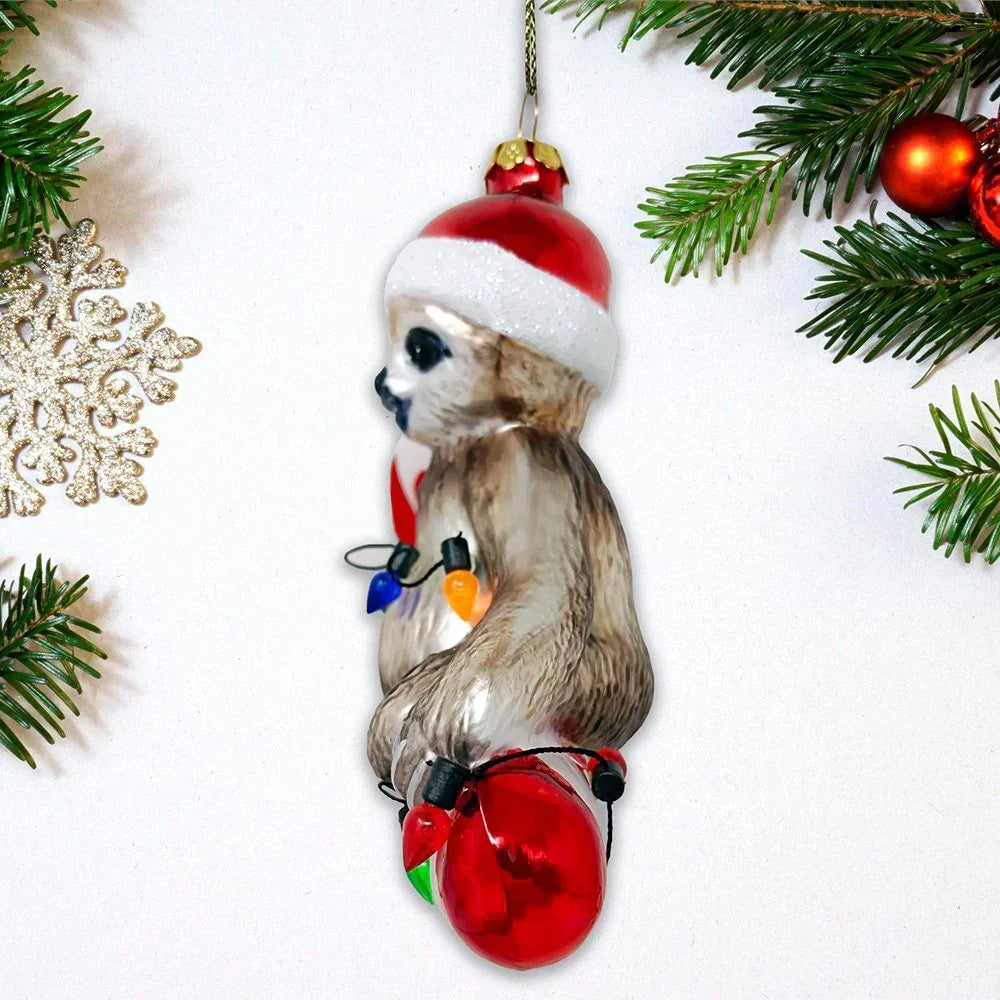 Sloth Christmas ornament with Santa hat and festive lights on a holiday tree branch