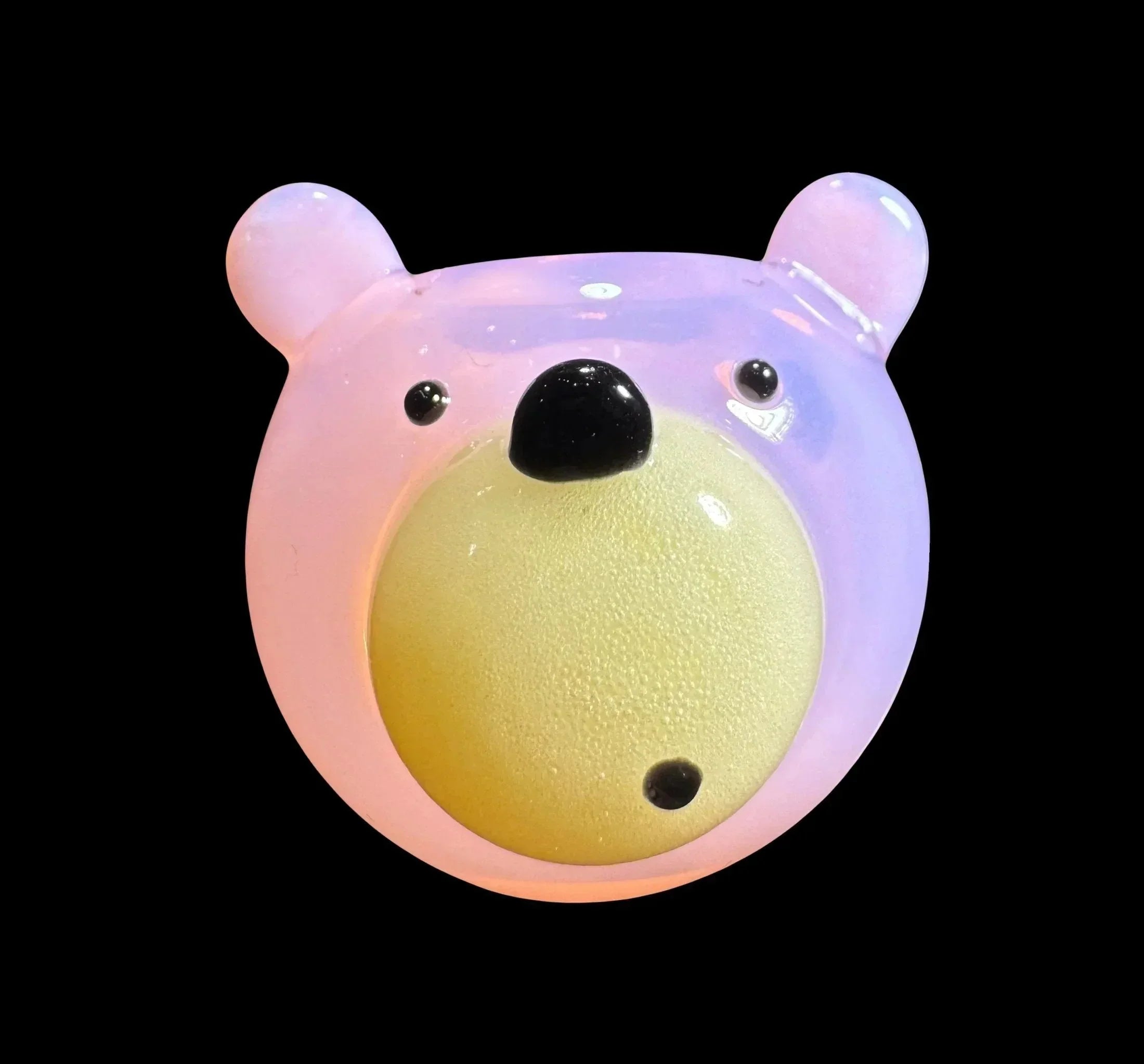 Pink and yellow bear-shaped glass carb cap accessory on black background