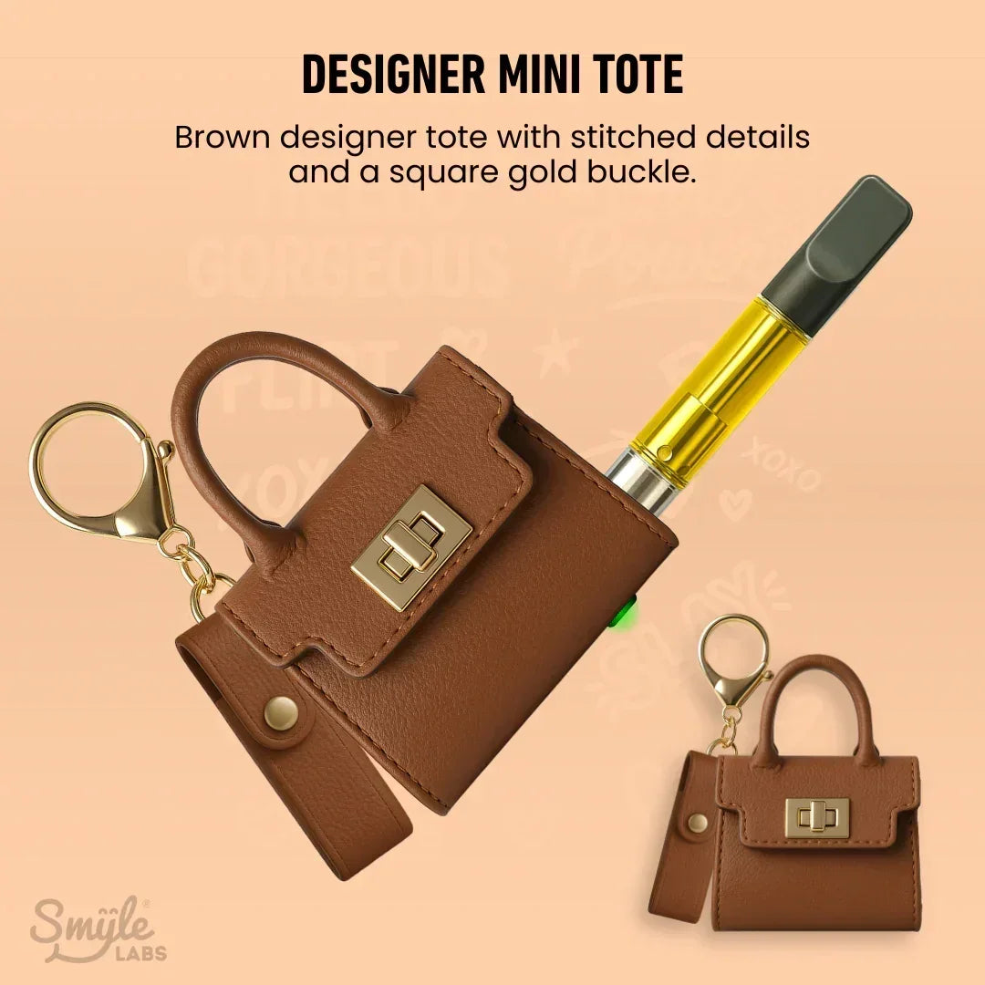 Brown mini tote keychain case with gold buckle, holding a vape pen cartridge.
