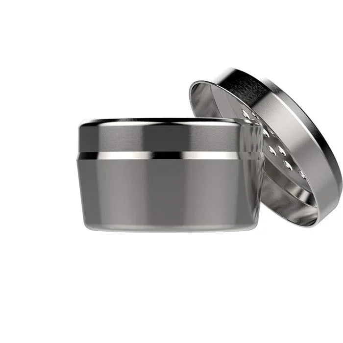 Stainless steel herb grinder with open lid and sharp teeth, for grinding dry herbs.