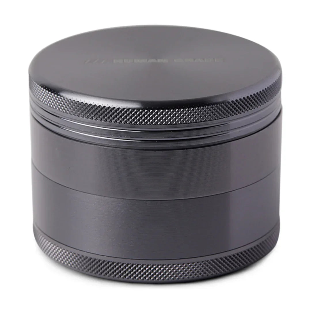Matte black metal herb grinder with textured grip and smooth lid on white background