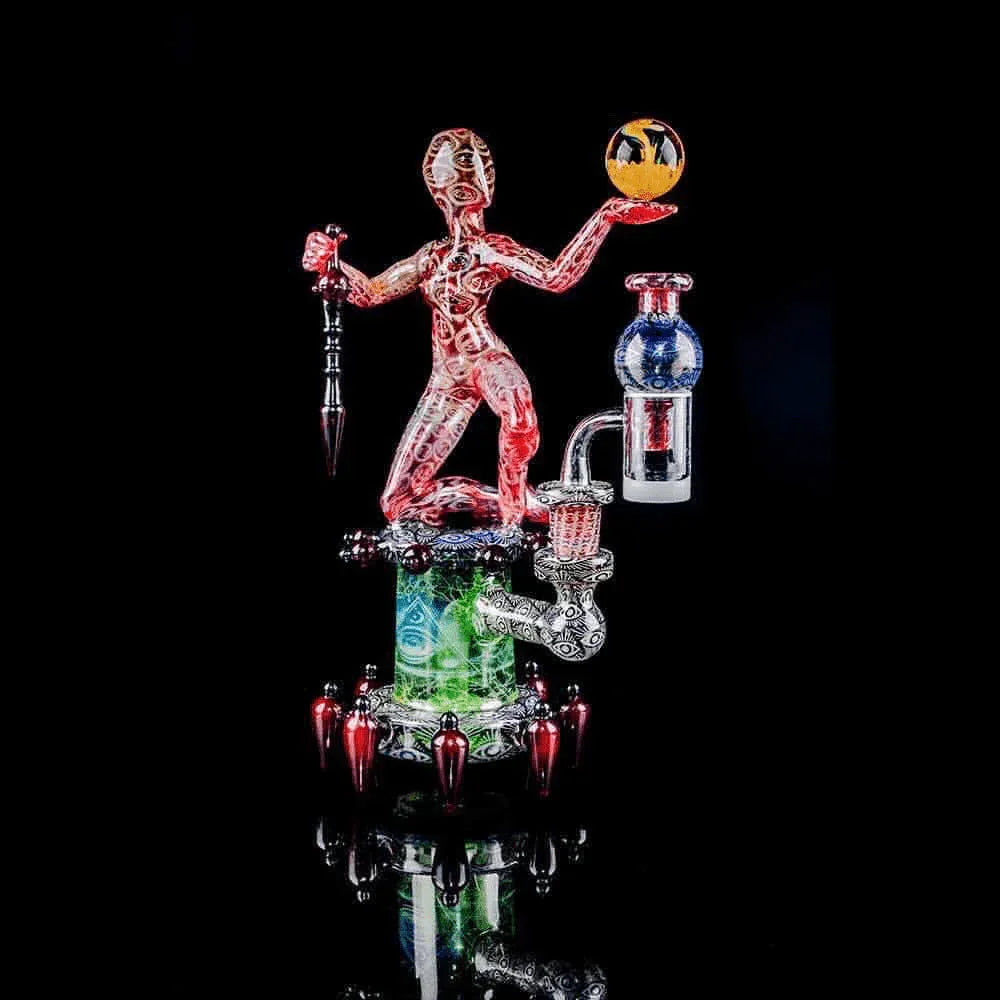 Heady glass dab rig featuring a red sculpted figure with orb, intricate patterns, and vibrant colors