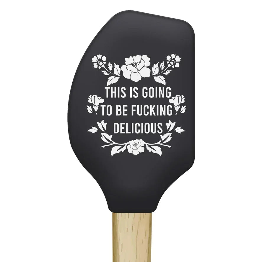 Black silicone kitchen spatula with floral design and humorous cooking quote in white text