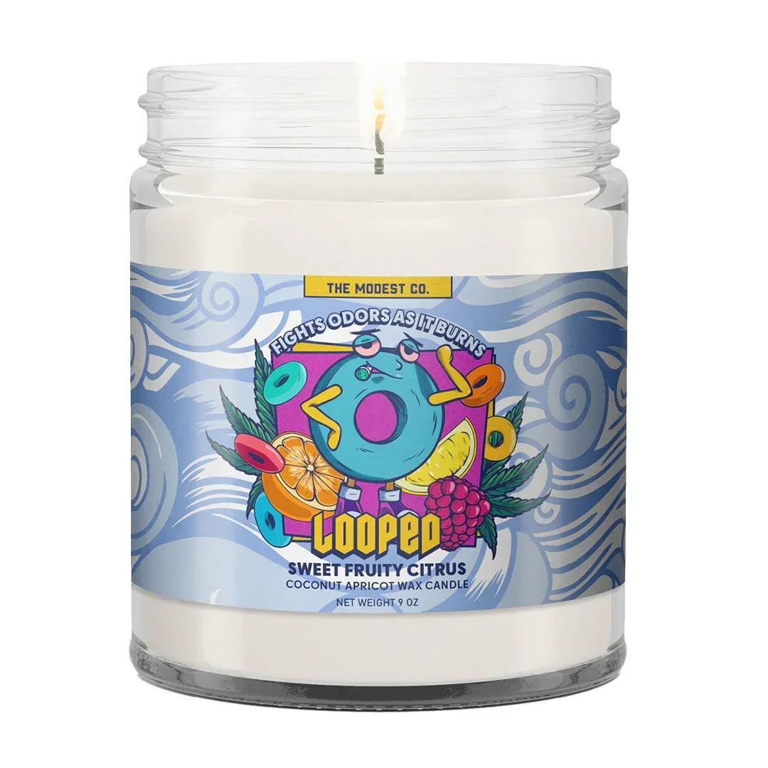 Sweet fruity citrus scented candle in a glass jar with colorful fruit label, burning wick