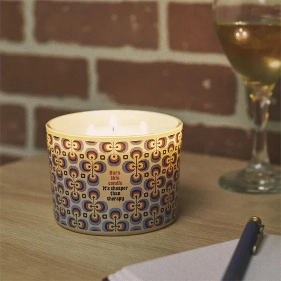 Lit patterned candle on table with wine glass, cozy home decor ambiance