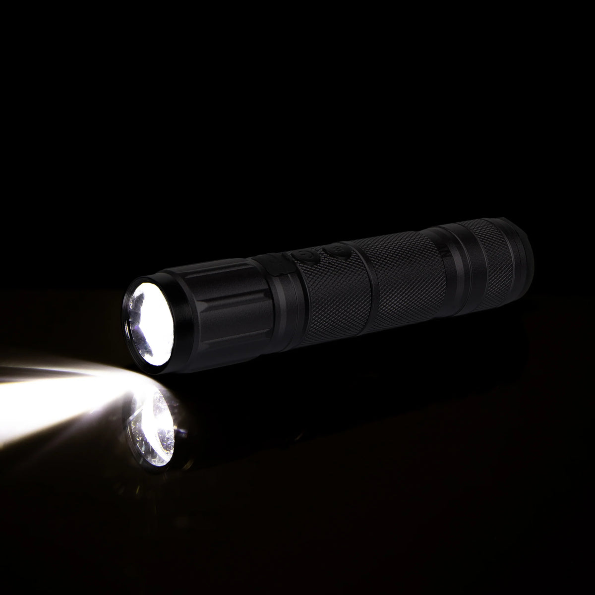 Black LED flashlight shining light on black background, close-up product photo