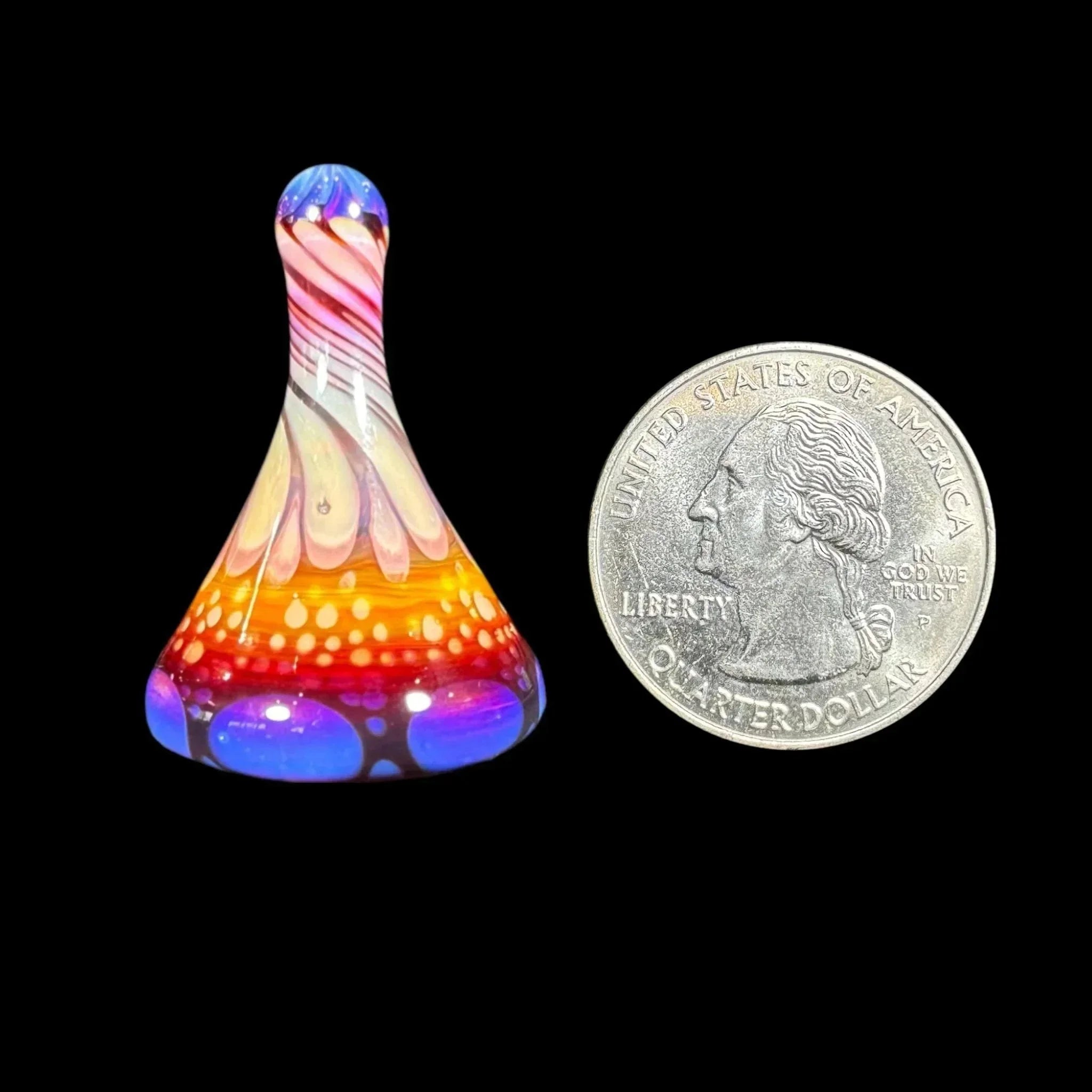 Colorful glass carb cap with intricate patterns beside a US quarter for size reference
