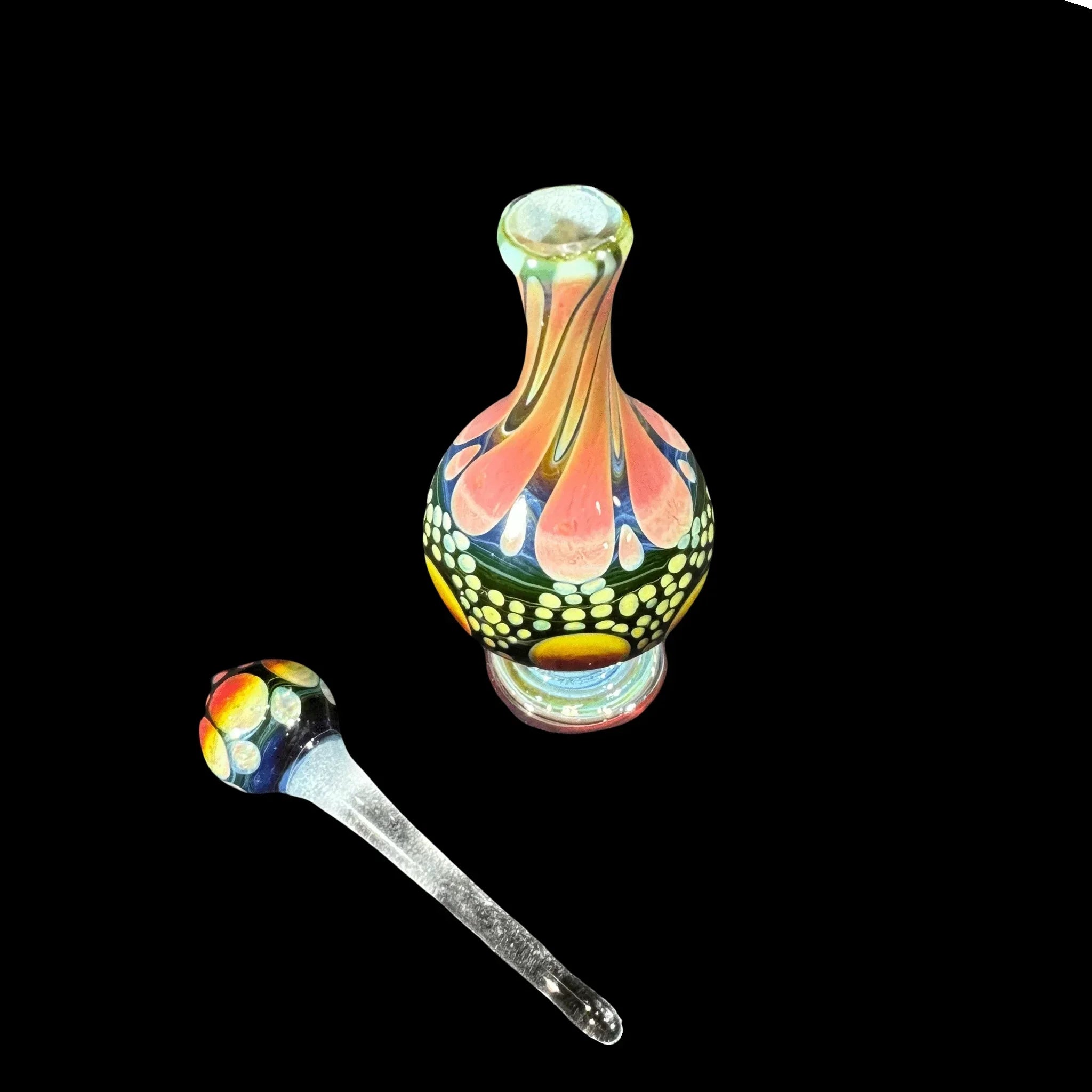 Colorful heady glass bottle and dab tool with intricate patterns on black background
