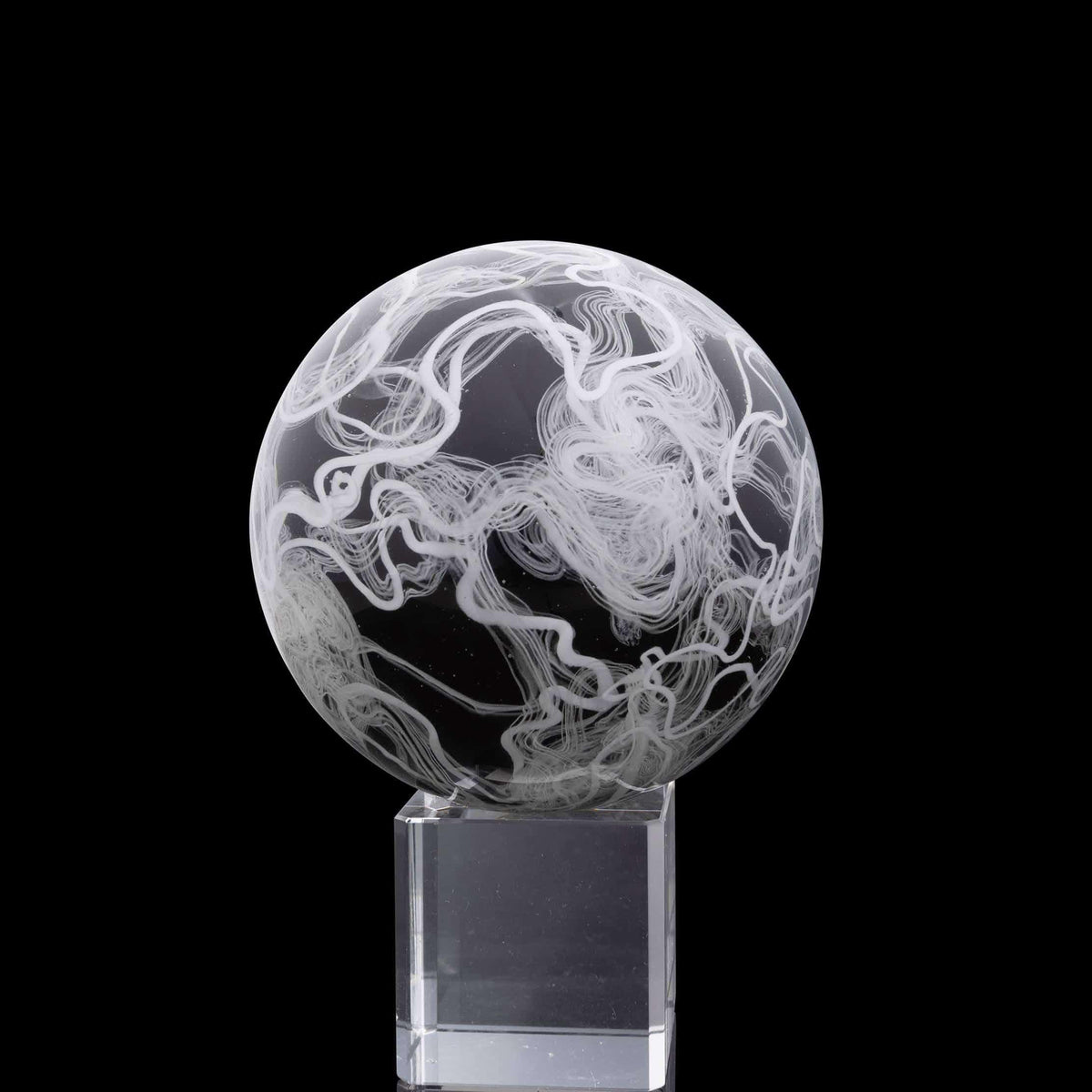 Black and white borosilicate glass marble with swirling patterns on a clear stand