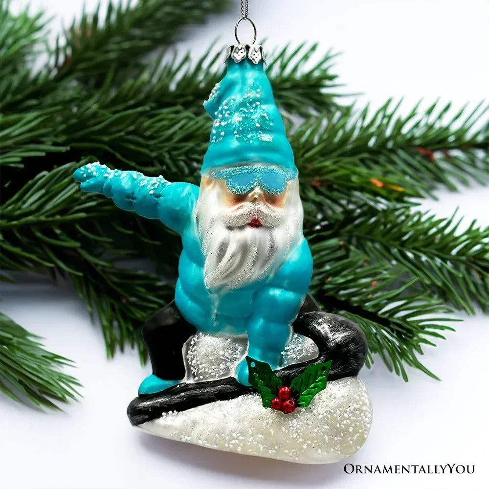 Christmas tree ornament of a gnome in blue snowboarding on glitter snow, pine branches background
