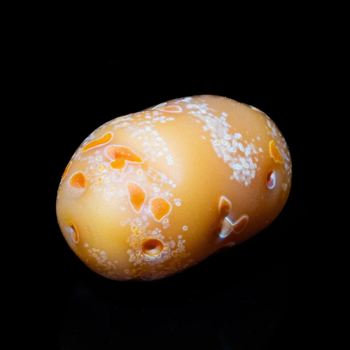Handcrafted glass pocket pipe resembling a potato with textured detailing on black background.