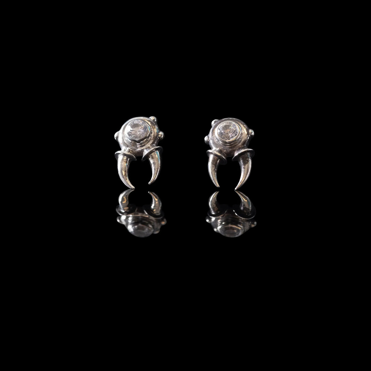 Pair of phenacite stud earrings with claw-like silver settings on a black background