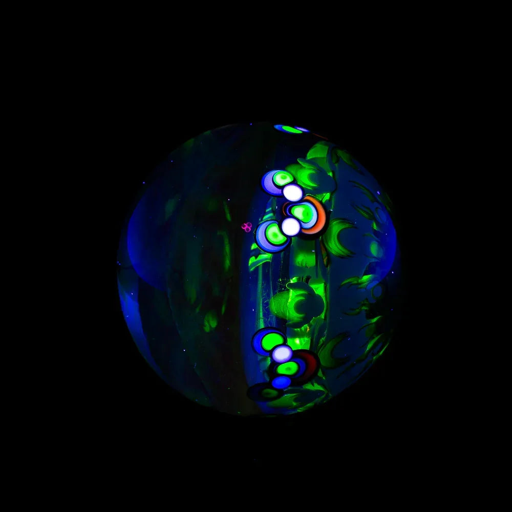 Hand-blown glass marble with glowing green and neon bubble patterns on a black background