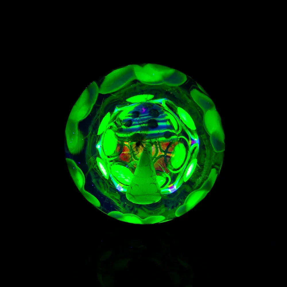Glowing green glass marble with intricate patterns and vibrant UV reactive design