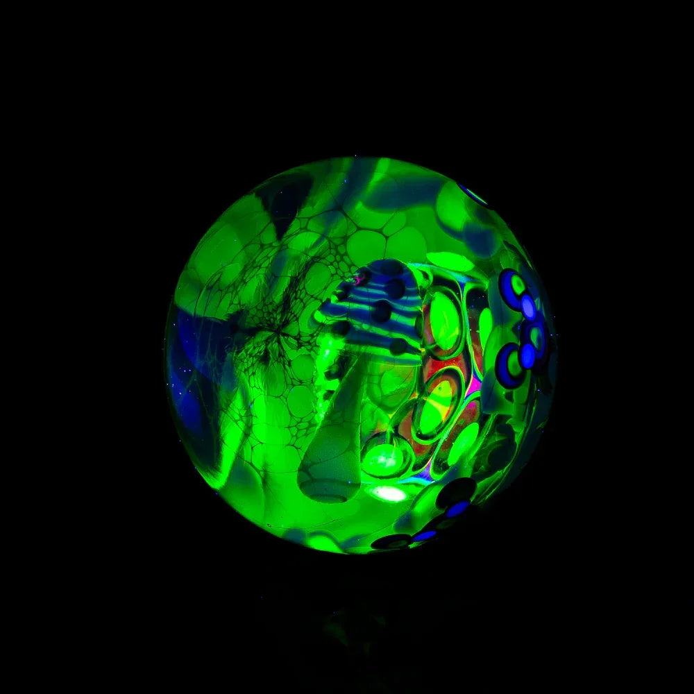 UV reactive heady glass marble with neon green and blue patterns on black background
