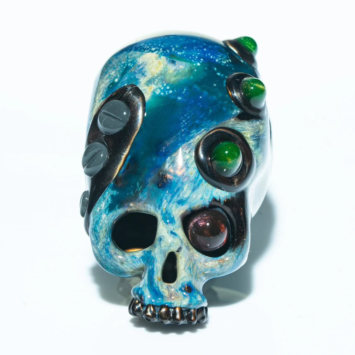 Hand-blown glass skull pendant with blue, green, and metallic galaxy accents on white background