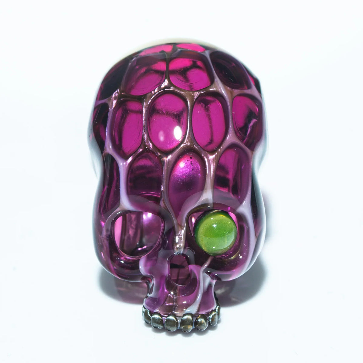 Purple honeycomb glass skull pendant with green accent eye on white background