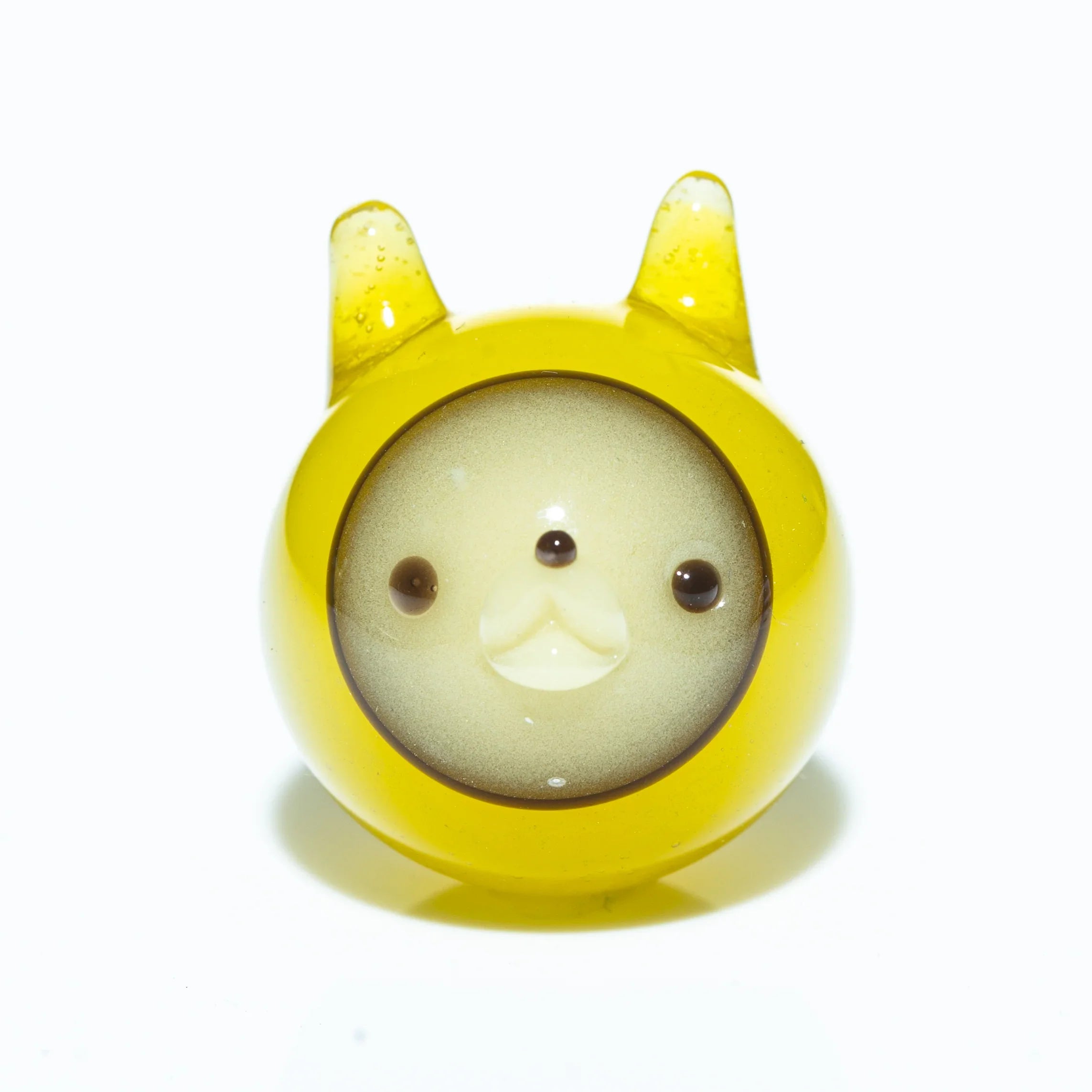 Yellow marble with cute animal face and ears, artisan glass accessory on white background