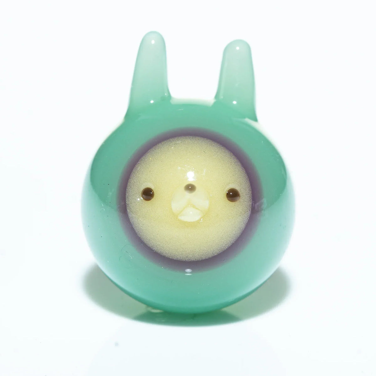 Seafoam green glass marble with cute animal face and ear-like details, white background