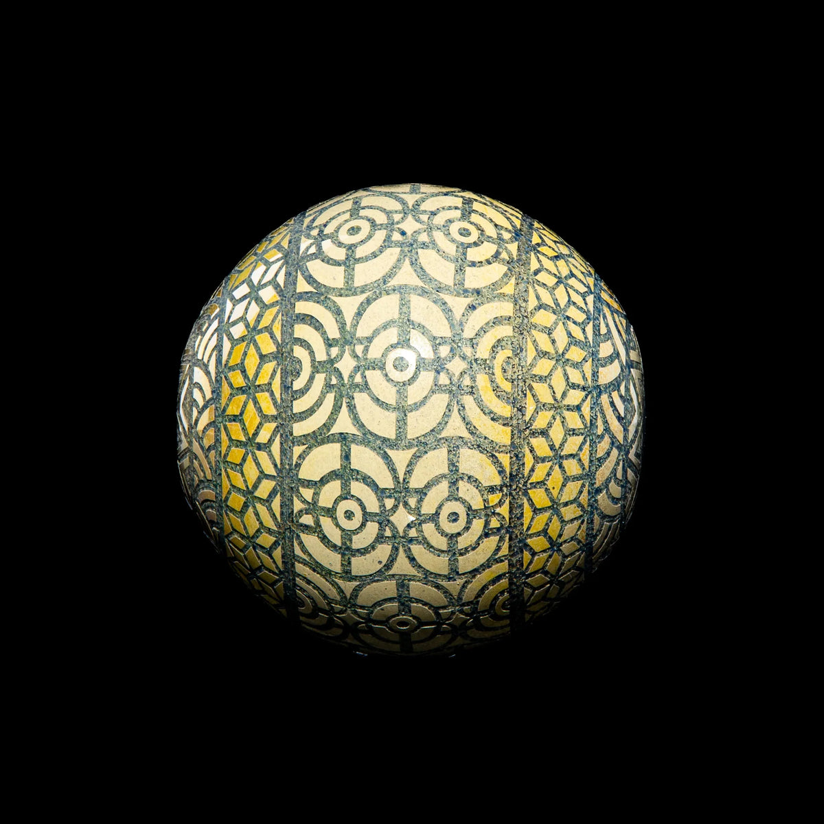 Geometric glass marble with intricate yellow and black circular and hexagon patterns