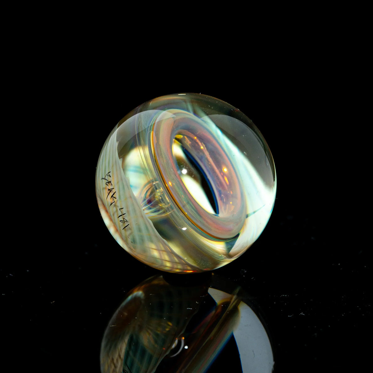 Toroidal clear glass marble with linework and reflective surface on black background