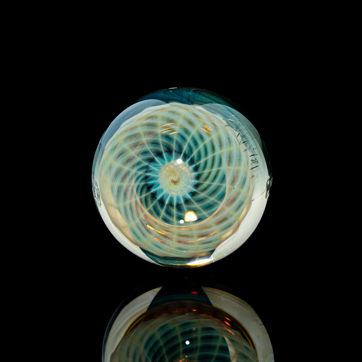 Toroidal glass marble with intricate spiral linework on a black reflective surface