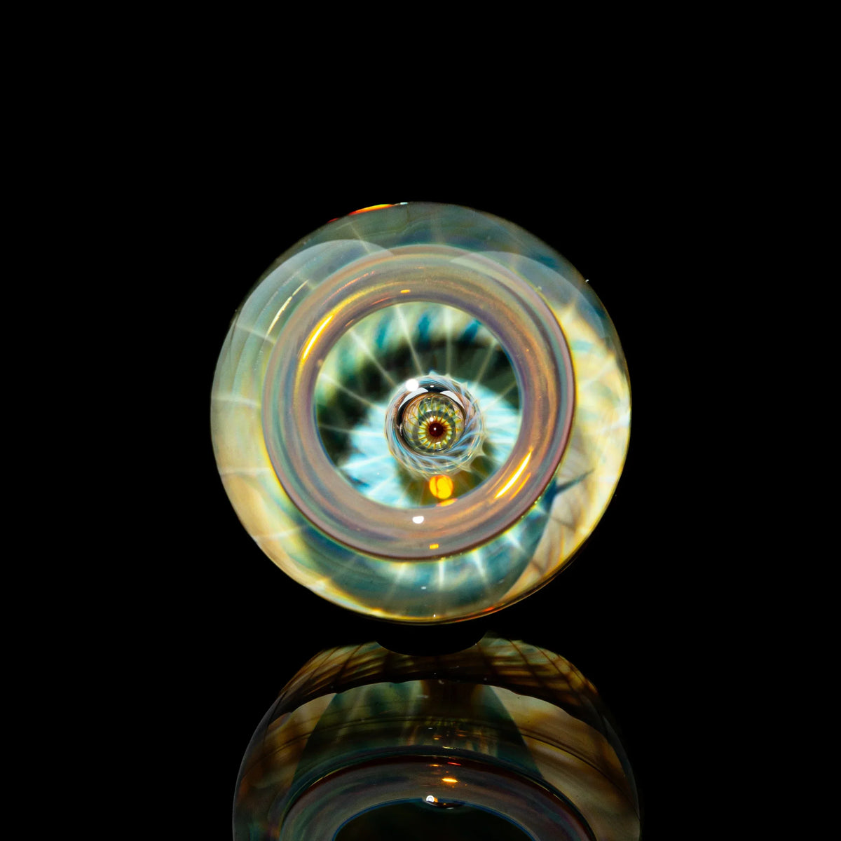 Toroidal glass marble with intricate linework on black reflective background