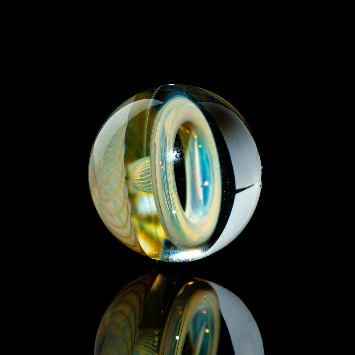 Handcrafted borosilicate glass marble with intricate toroidal linework on black background