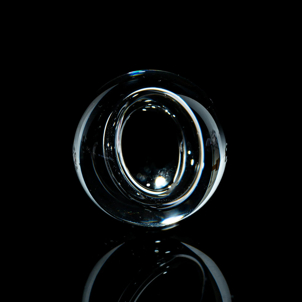 Clear toroidal glass marble with glossy finish on a black reflective background