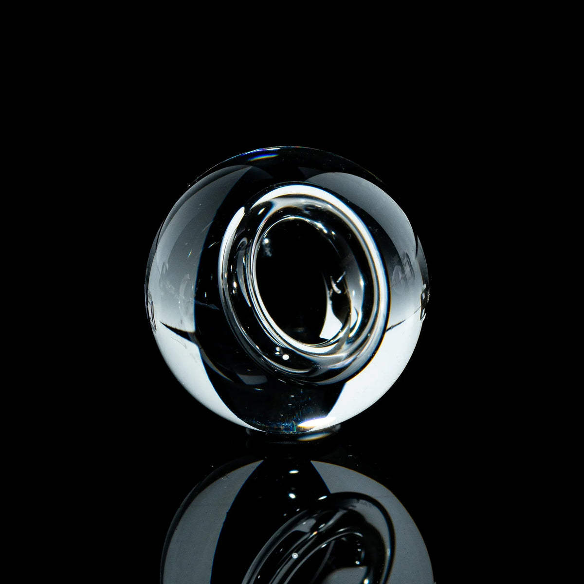 Clear toroidal glass marble with reflective finish on black background